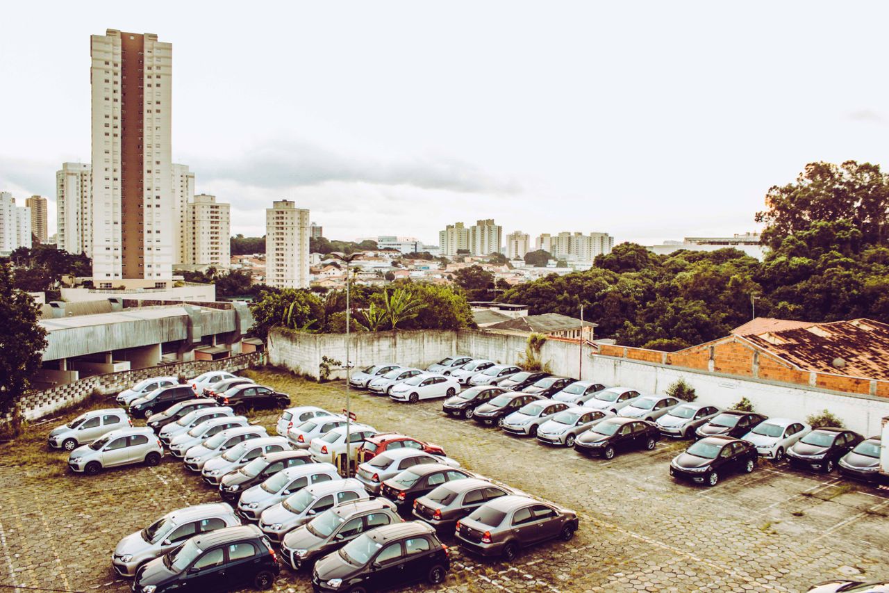 High angle view of cars parked in a city lot with skyline in the background.